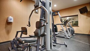 Un gimnasio con equipo de ejercicio, un reloj y una ventana.