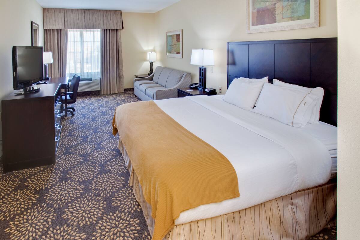 Une chambre d’hôtel avec un grand lit, un bureau avec un ordinateur, un canapé et une télévision.