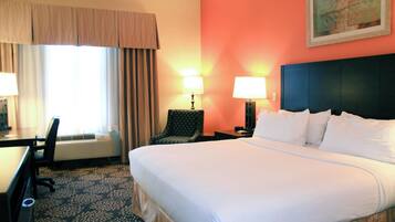 A hotel room with a large bed, two bedside lamps, a desk with a chair, and a window with curtains.