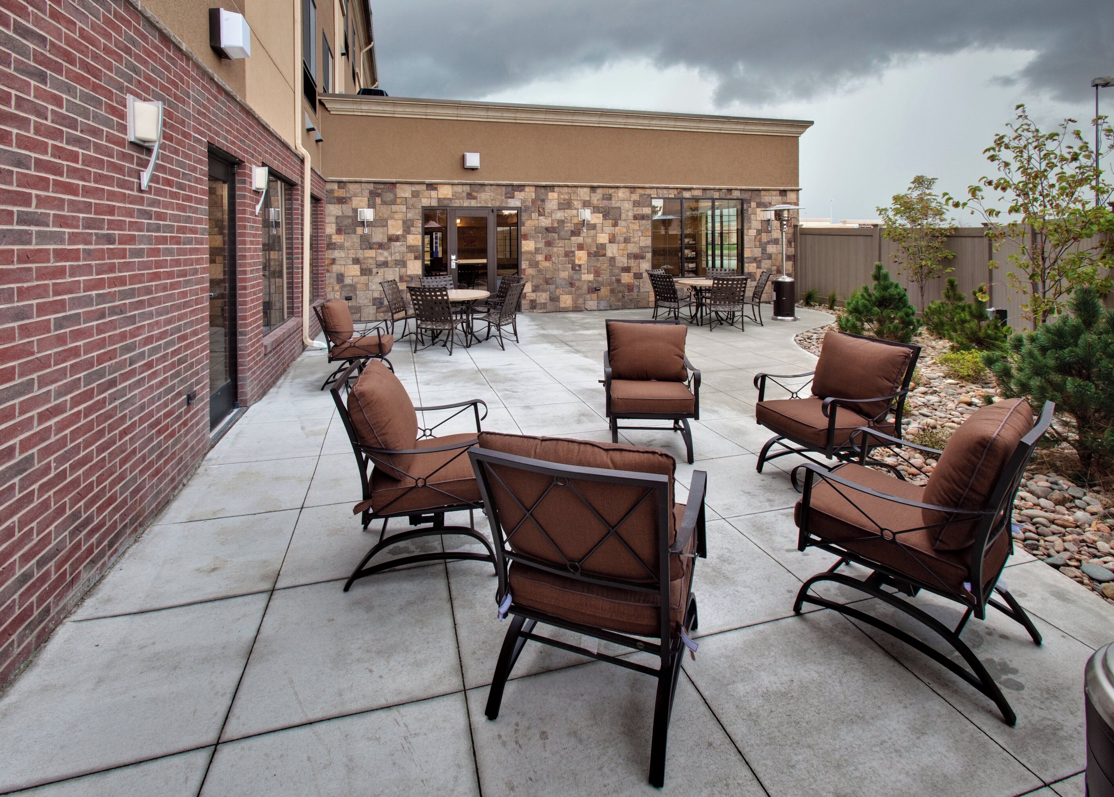 An outdoor patio with stone walls, a brick building, and a stormy sky.