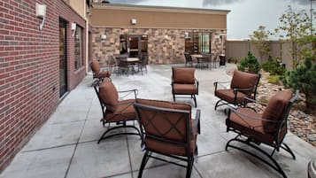 An outdoor patio with stone walls, a brick building, and a stormy sky.