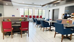 A modern cafe with red and blue seating, large windows, and a coffee station. - Holiday Inn Express Hotel & Suites Grand Island by IHG (Grand Island)