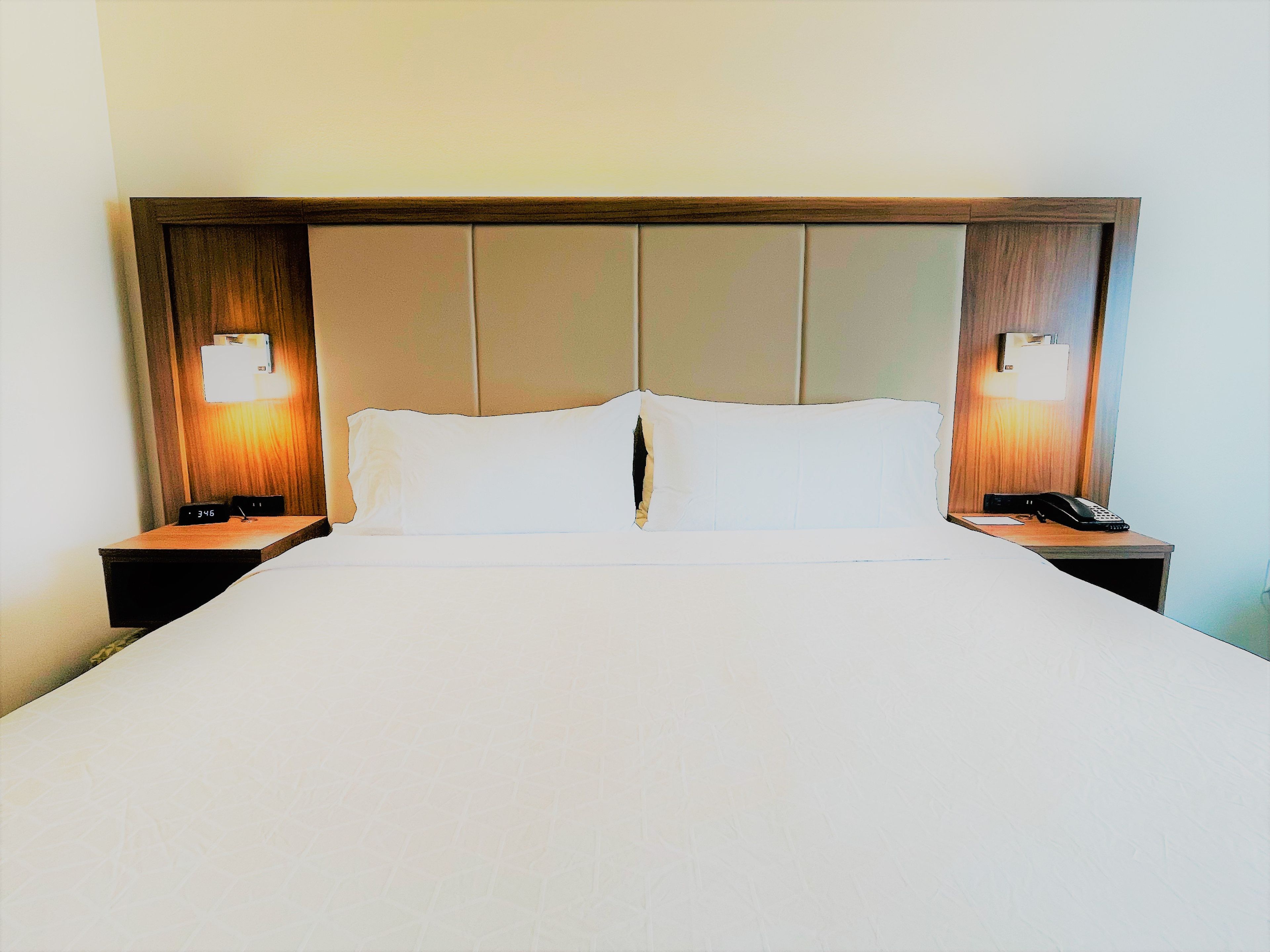 Habitación de hotel con una cama grande, dos mesitas de noche y un teléfono de pared.