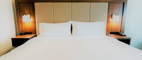 Habitación de hotel con una cama grande, dos mesitas de noche y un teléfono de pared.