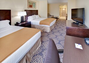 A hotel room with two beds, a desk, a TV, and a sofa.
