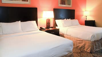 A hotel room with two beds, nightstands with lamps, and artwork on the walls.