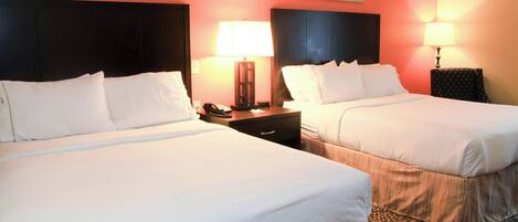 A hotel room with two beds, nightstands with lamps, and artwork on the walls.