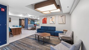 A modern lounge area with a blue sofa, a wooden coffee table, and a patterned rug. - Holiday Inn Express & Suites Maumelle - Little Rock NW by IHG (Maumelle)