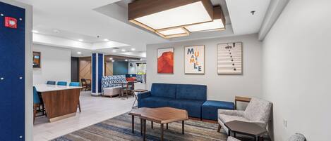A modern lounge area with a blue sofa, a wooden coffee table, and a patterned rug.