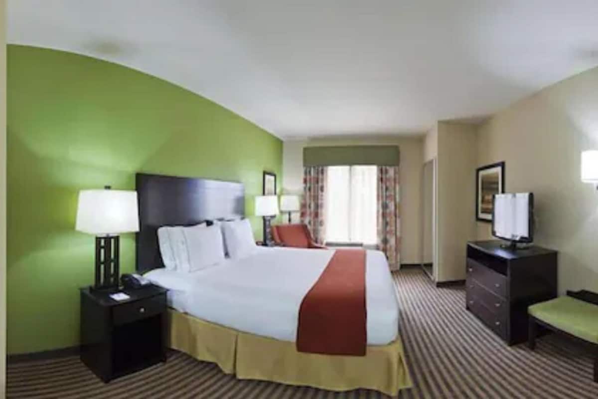 Une chambre d’hôtel comprenant un lit, des tables de chevet, un bureau, une chaise et un téléviseur.