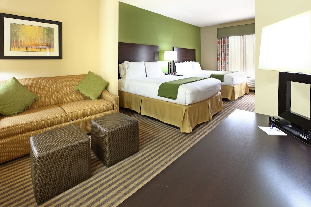 Une chambre d’hôtel avec un lit, un canapé, une télévision et un tableau au mur.