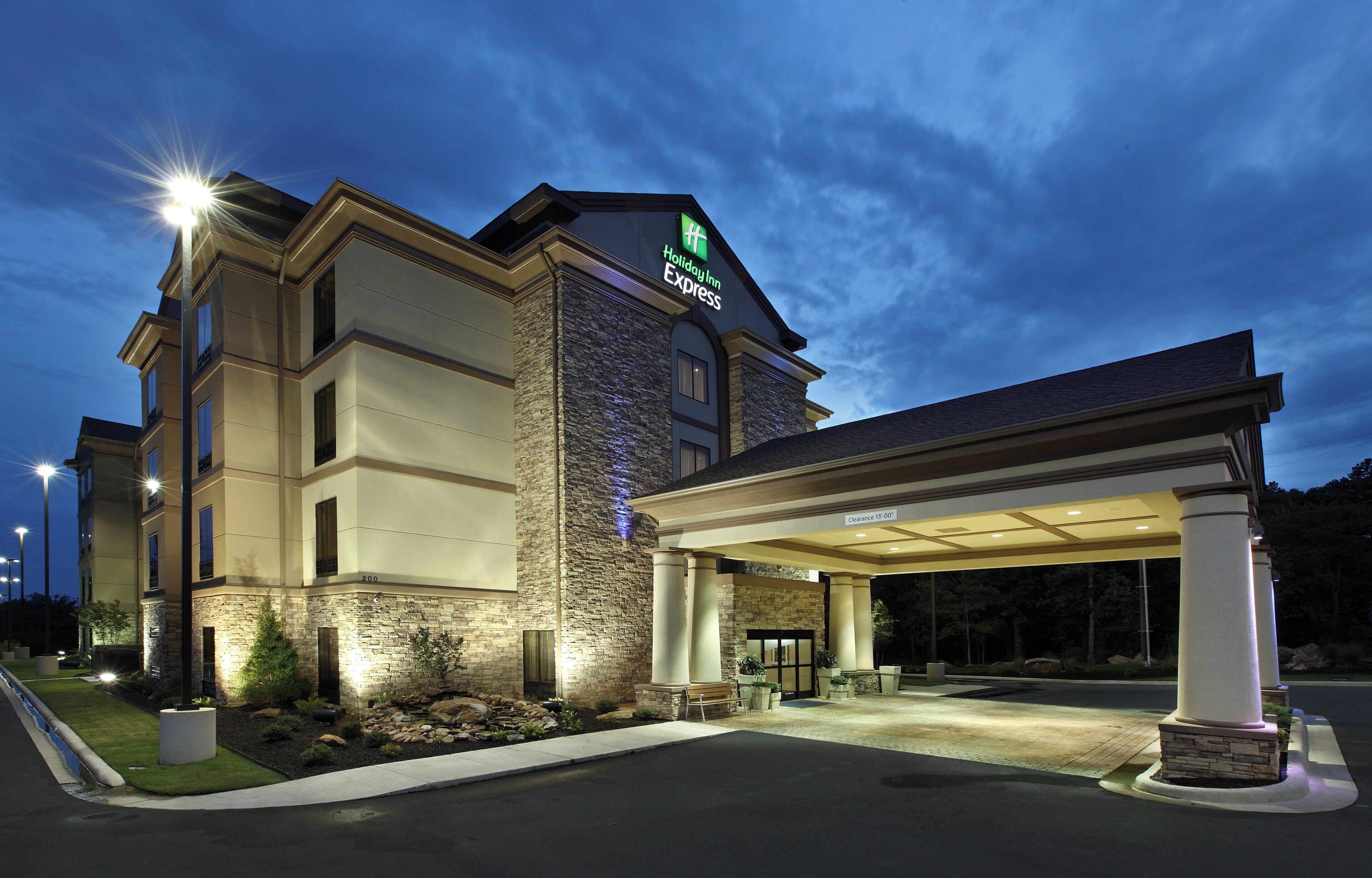Un hotel Holiday Inn Express con fachada de piedra, un acceso cubierto e iluminación exterior.