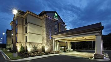 A Holiday Inn Express hotel with a stone facade, a covered entrance, and a well-lit exterior.