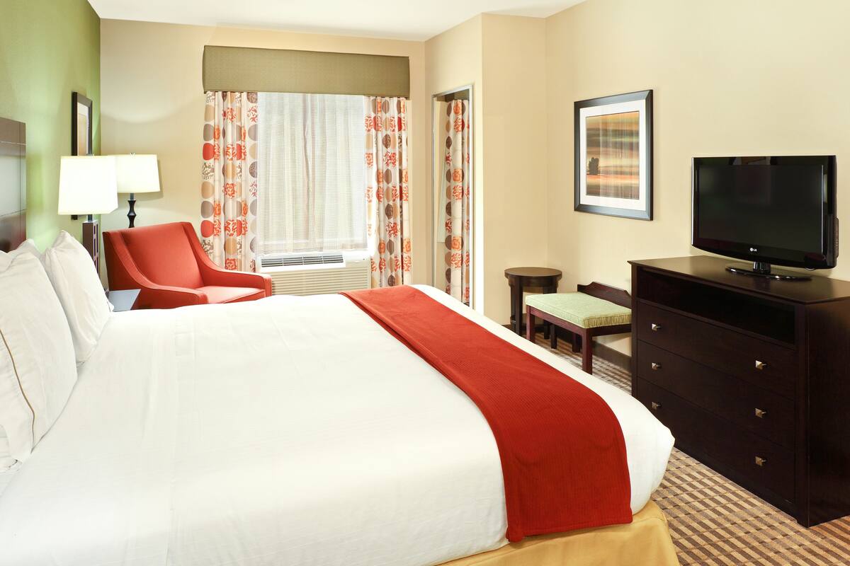 Une chambre d’hôtel avec un grand lit, une télévision, un bureau et une chaise.