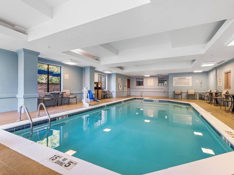 Una piscina interior con agua cristalina, una estación de socorristas y sillas de descanso.
