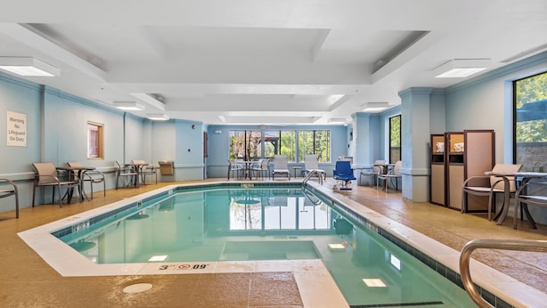 An indoor swimming pool with clear water, surrounded by lounge chairs and tables. - Holiday Inn Express & Suites Maumelle - Little Rock NW by IHG (Maumelle)