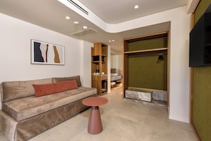 A modern living room with a sofa, a round table, and a built-in shelving unit. - Blue Sea Beach Affiliated by Melia (Hersonissos)