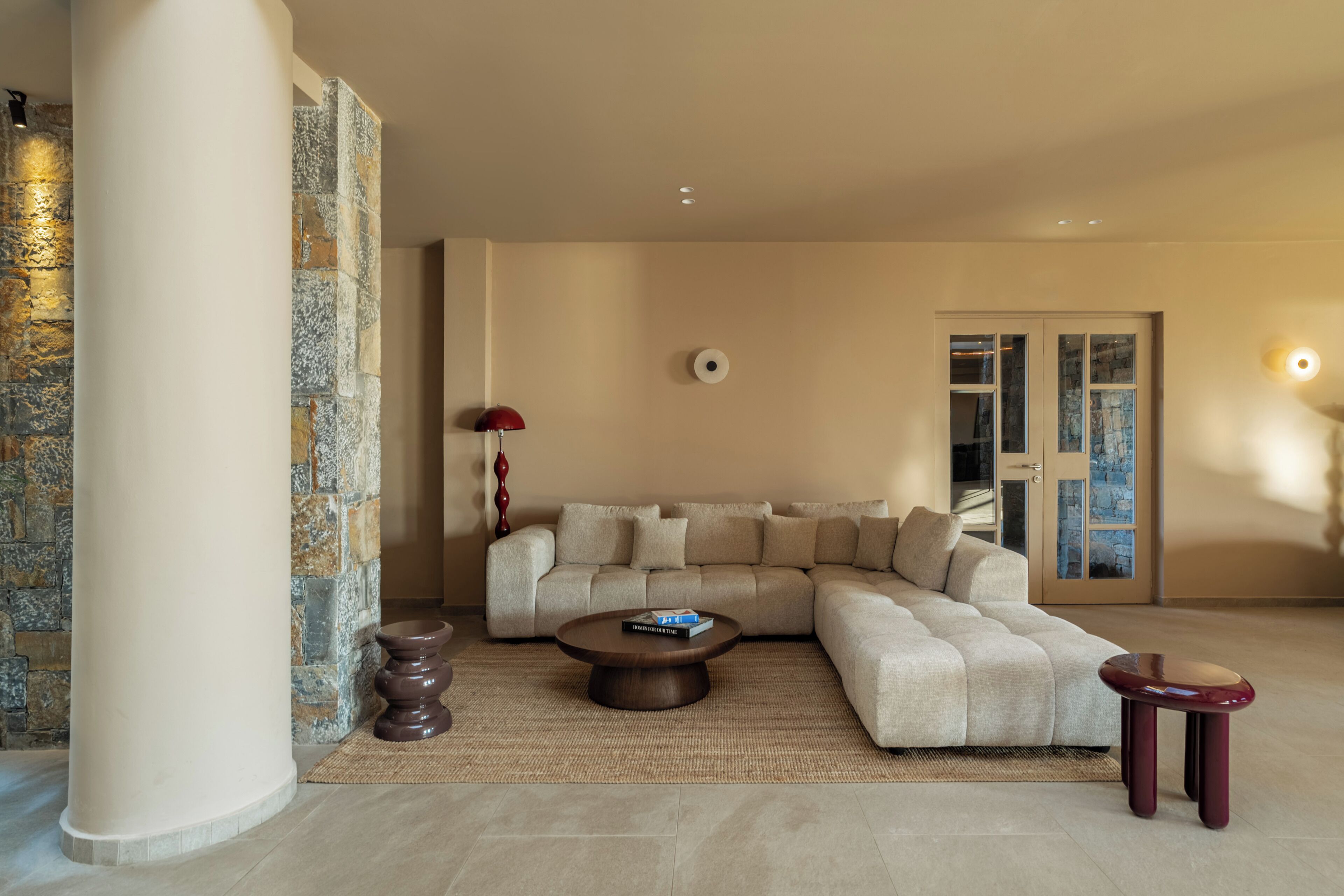 Una sala de estar moderna con un sofá modular, una mesa de centro redonda y una pared de acento de piedra.