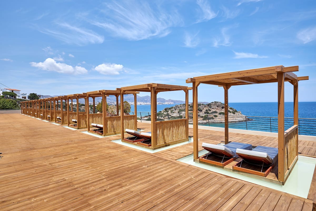 A wooden deck with sun loungers and a view of the sea.