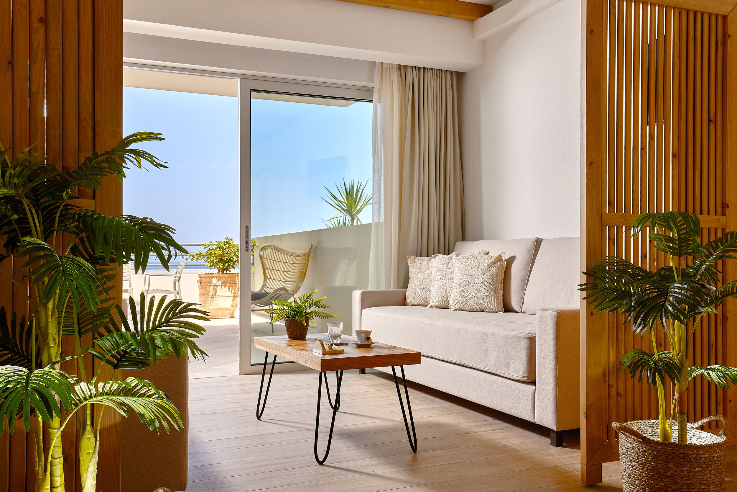 A modern living room with a sofa, a wooden coffee table, and potted plants.