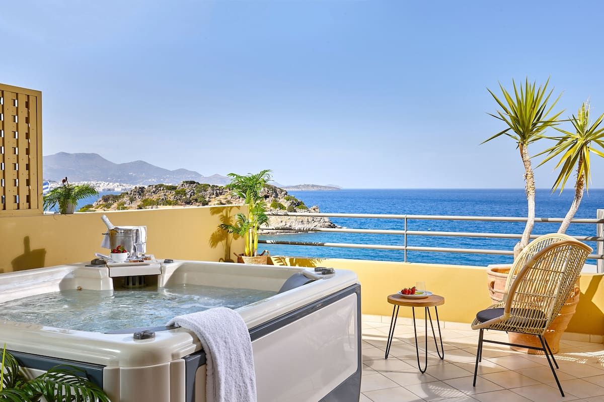 A hot tub on a balcony with a view of the sea and mountains.