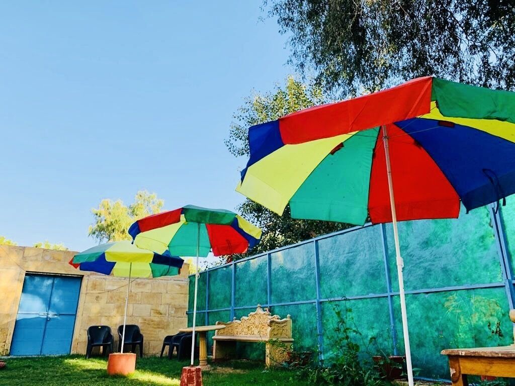 A patio area with multiple colorful umbrellas, a stone wall, and outdoor seating.