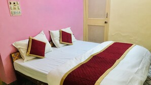 Een bed met wit en rood beddengoed, een houten frame en een roze muur met stopcontacten.