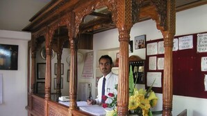Een houten receptiebalie, een man achter de balie en verschillende borden aan de muur.