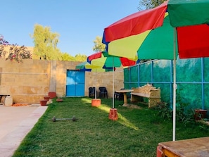 A courtyard with outdoor seating, a blue door, and colorful umbrellas.