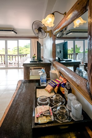 A hotel reception area with a wooden counter, a large mirror, and a view of the outdoor terrace.