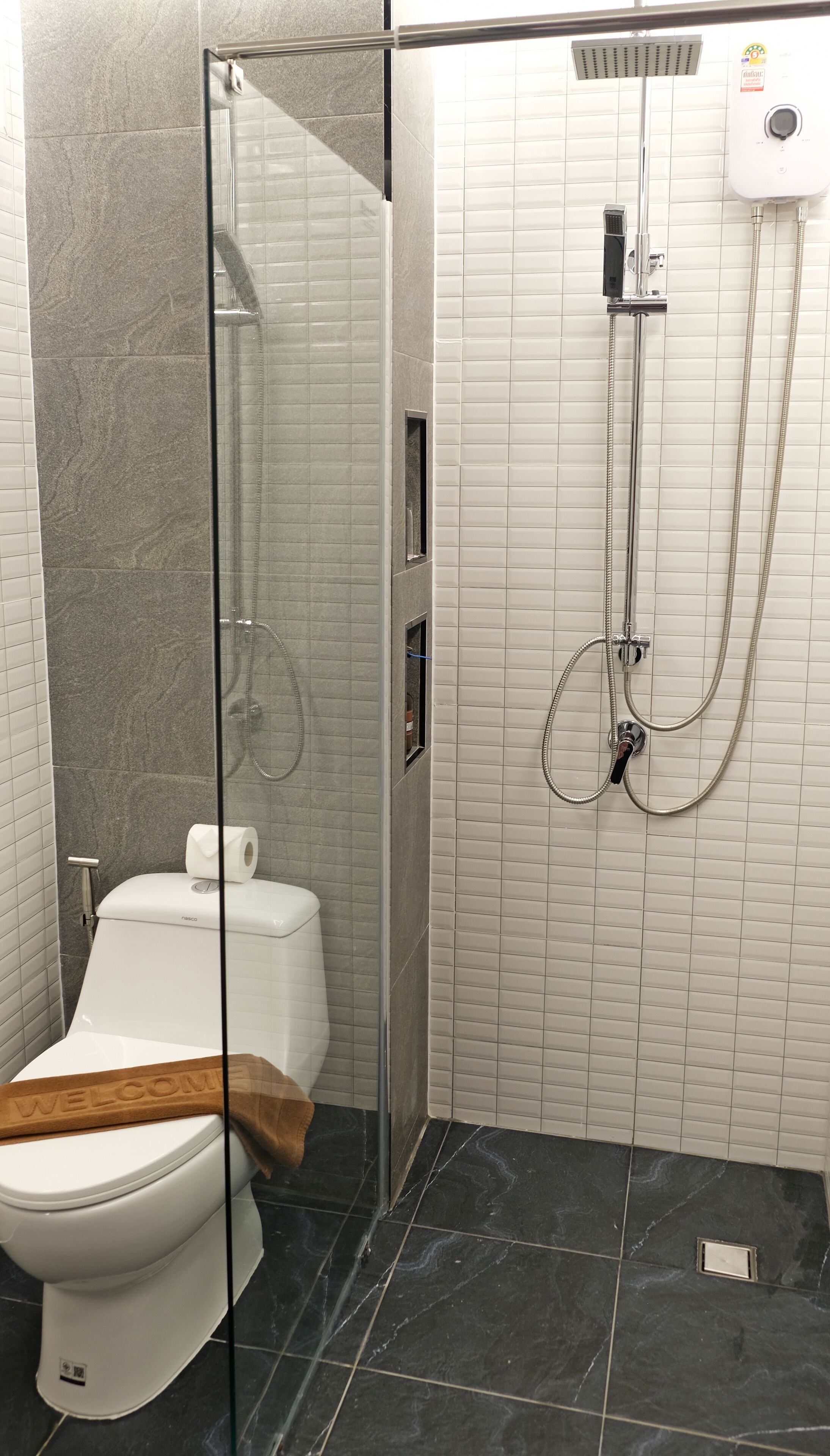 Ein modernes Badezimmer mit Duschkabine aus Glas, Toilette und Durchlauferhitzer.