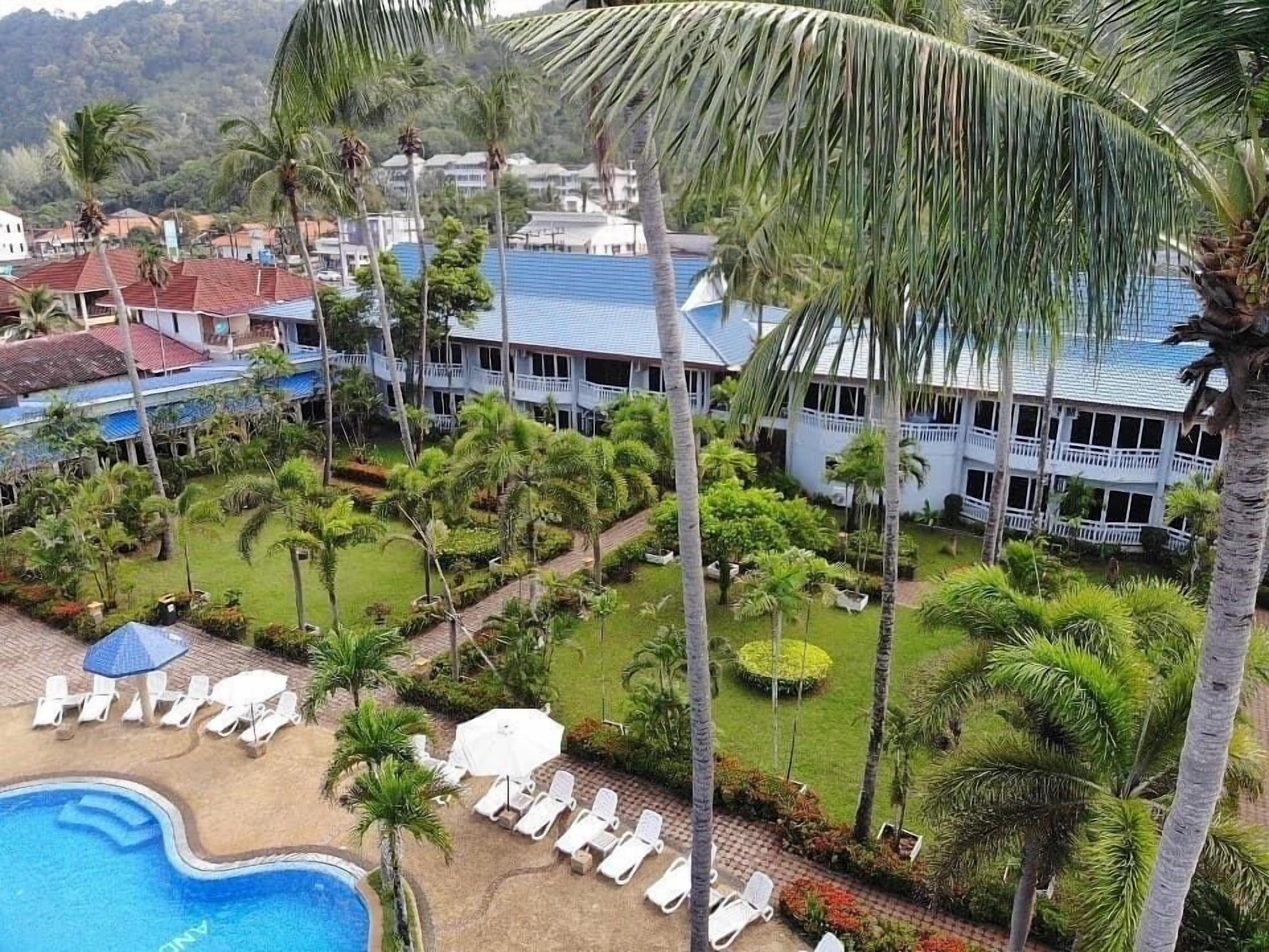 Un resort con piscina, sillas de descanso y palmeras.