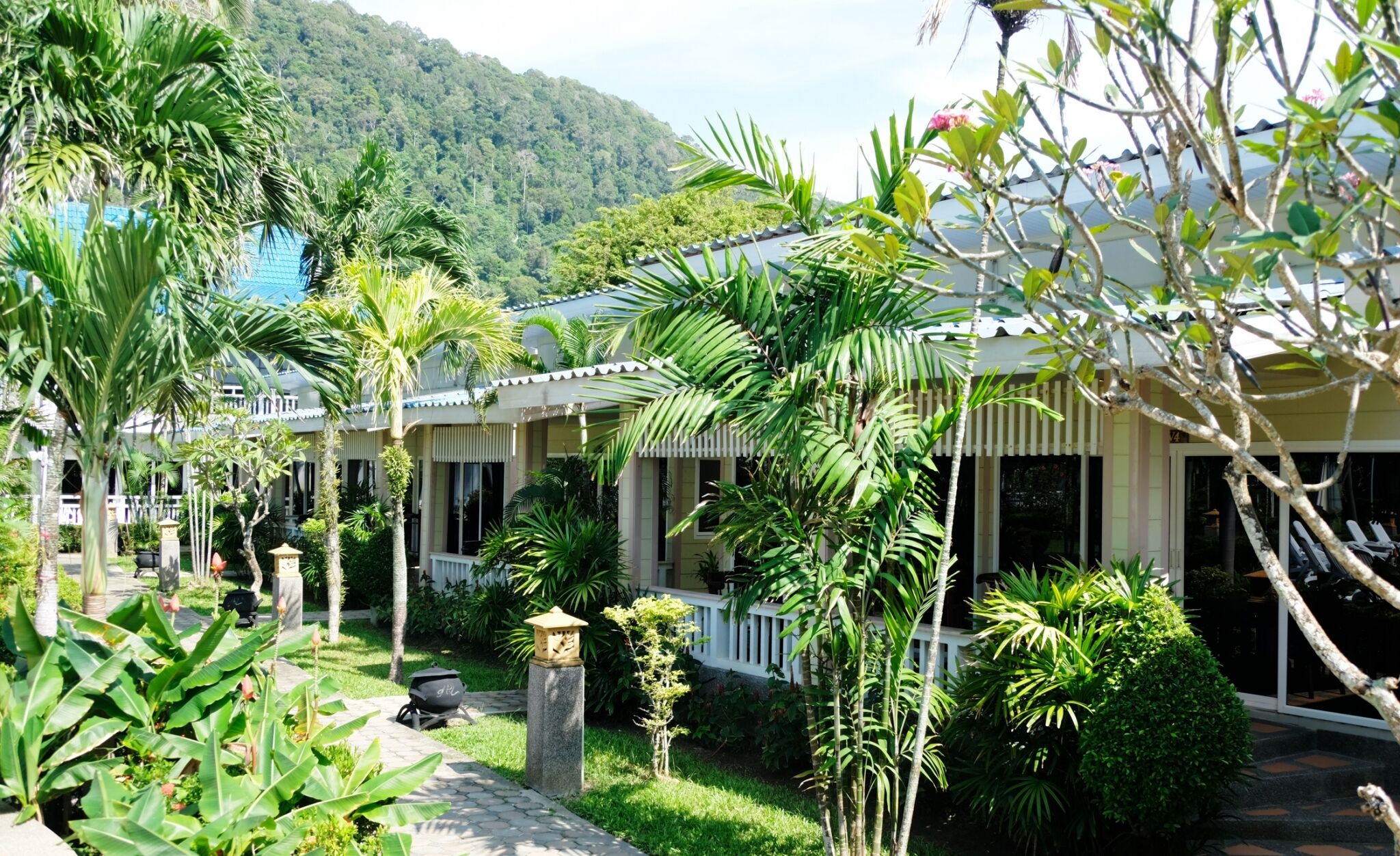 Een resort met meerdere villa's, weelderige groene begroeiing en een bergachtig landschap.