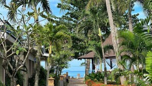 A pathway lined with palm trees and a view of the ocean. - Andaman Lanta Resort (Ko Lanta)