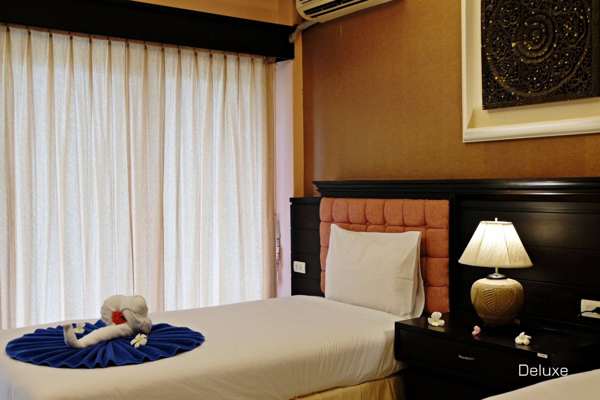 A hotel room with a neatly made bed, a bedside lamp, and a decorative wall piece.