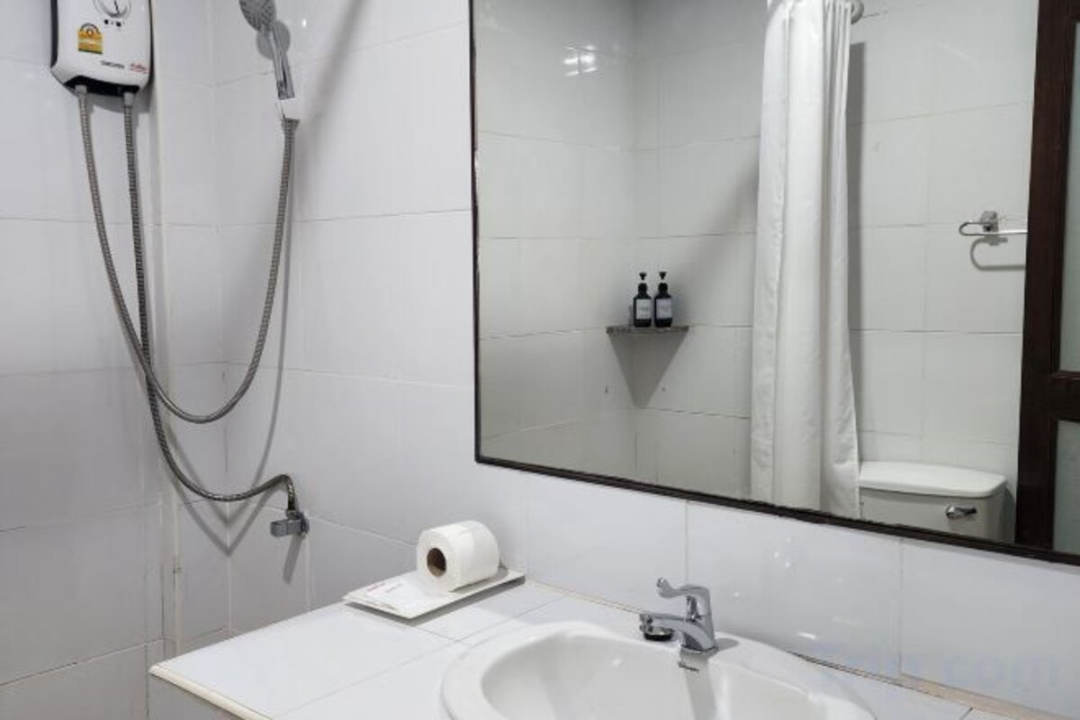 Een badkamer met een witte wastafel, een spiegel, een douche en een handdoekrek.