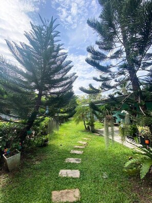 A garden pathway with a stone border, surrounded by lush greenery and trees. - The Palace Aonang Resort (Krabi)