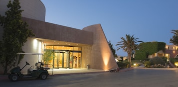 Un edificio moderno con un diseño arquitectónico único, que presenta una entrada curva y un carrito de golf estacionado afuera.