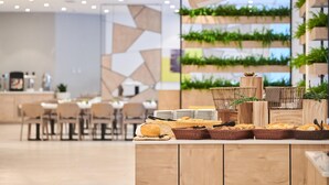 A modern dining area with a buffet setup, including bread and baskets, in a contemporary setting with geometric wall designs and greenery. - Garden Suites Park Plava Laguna (Porec)