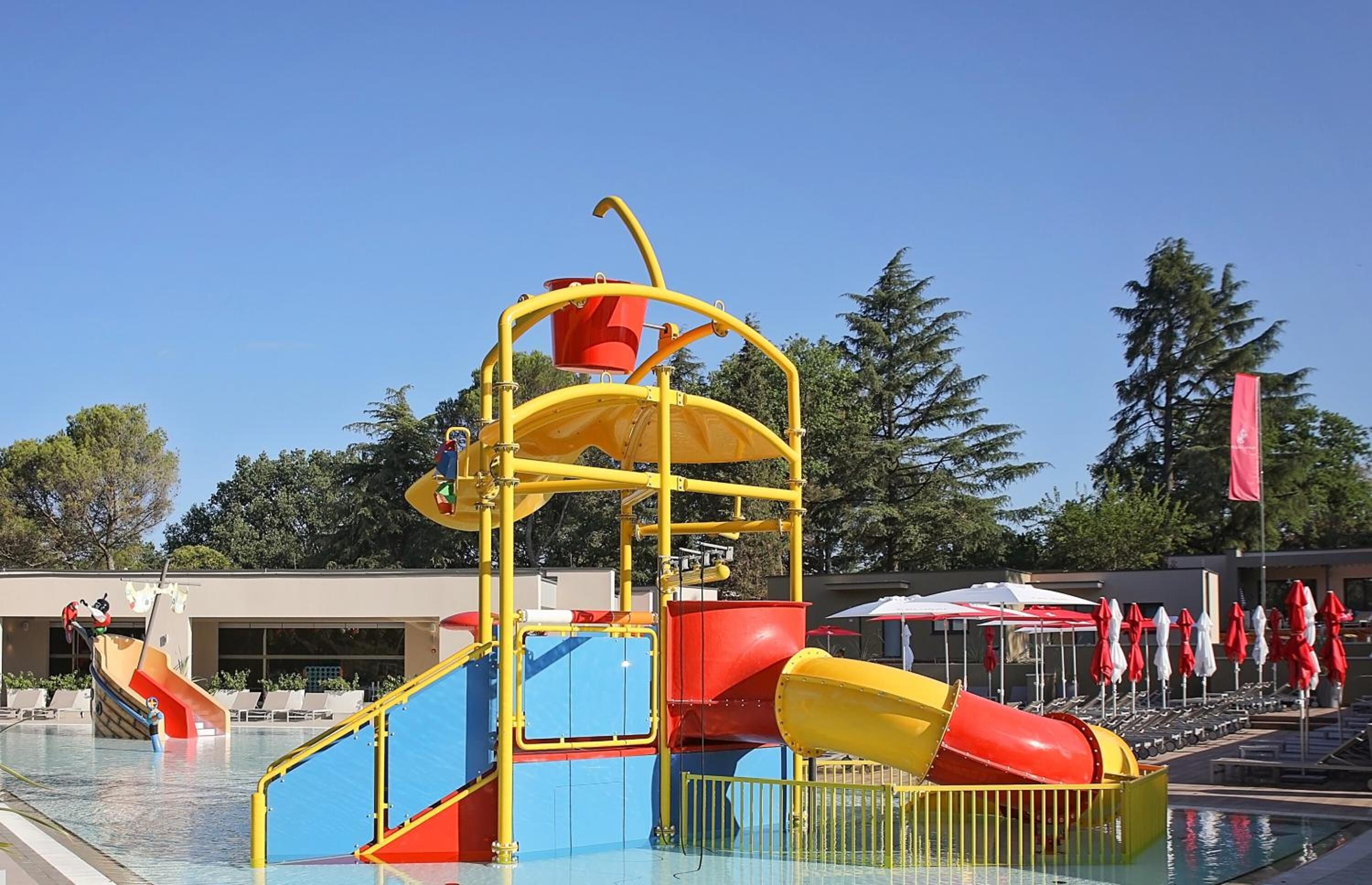 A pool area with a water play structure, including slides and a climbing area.