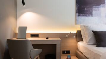 Quarto de hotel moderno com escrivaninha, cadeira e cama.