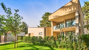 A modern two-story building with large windows and a flat roof, surrounded by well-maintained greenery. - Garden Suites Park Plava Laguna (Porec)