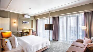A hotel room with a bed, a sofa, a desk, and a TV.