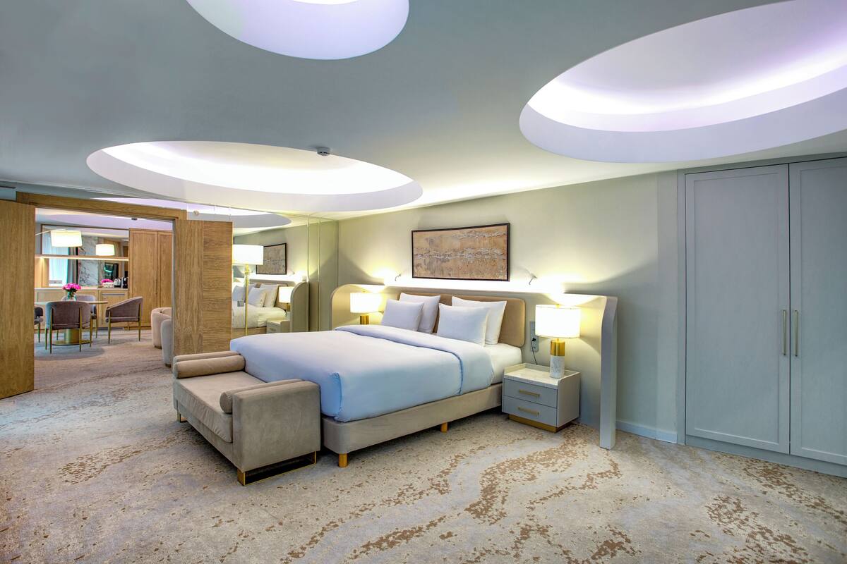 A hotel room with a large bed, bedside tables, a desk, and a wardrobe.