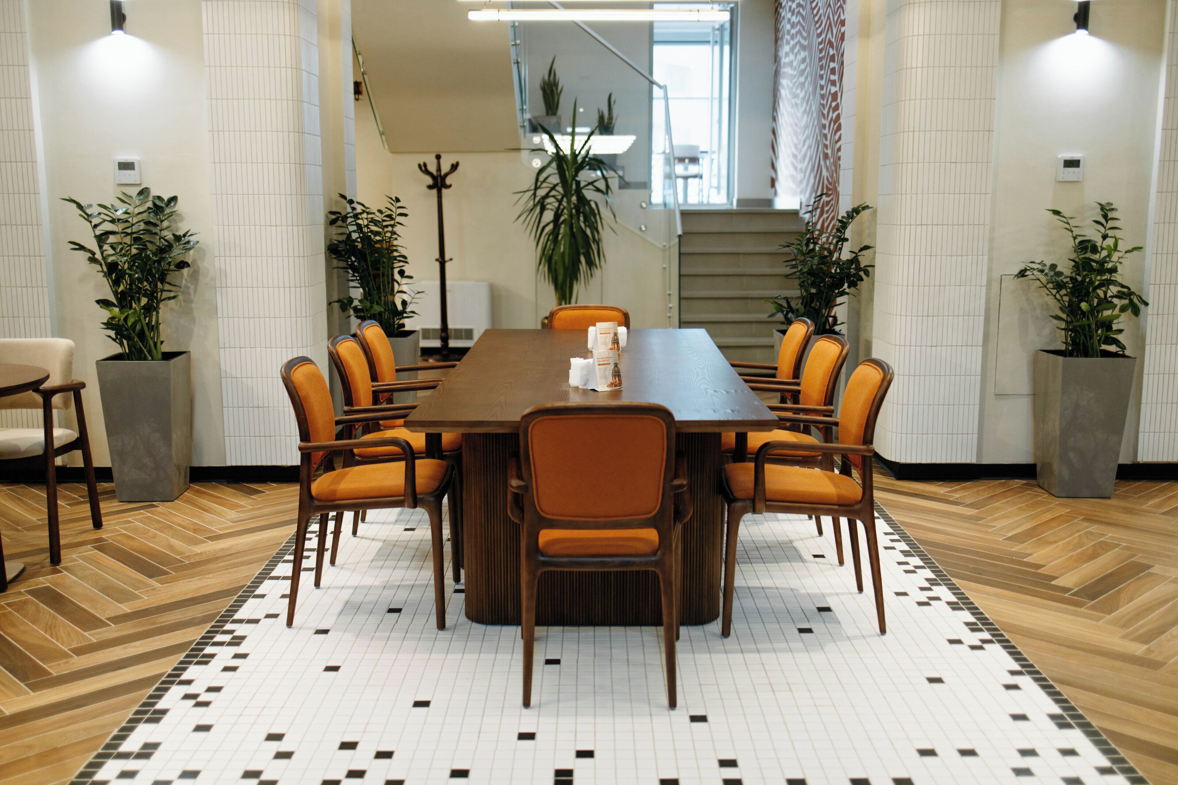 A conference room with a long table, six chairs, and potted plants.