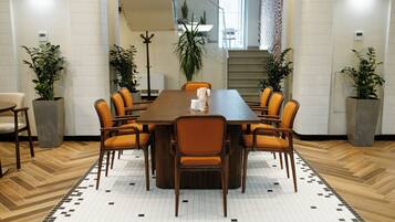 A conference room with a long table, six chairs, and potted plants.
