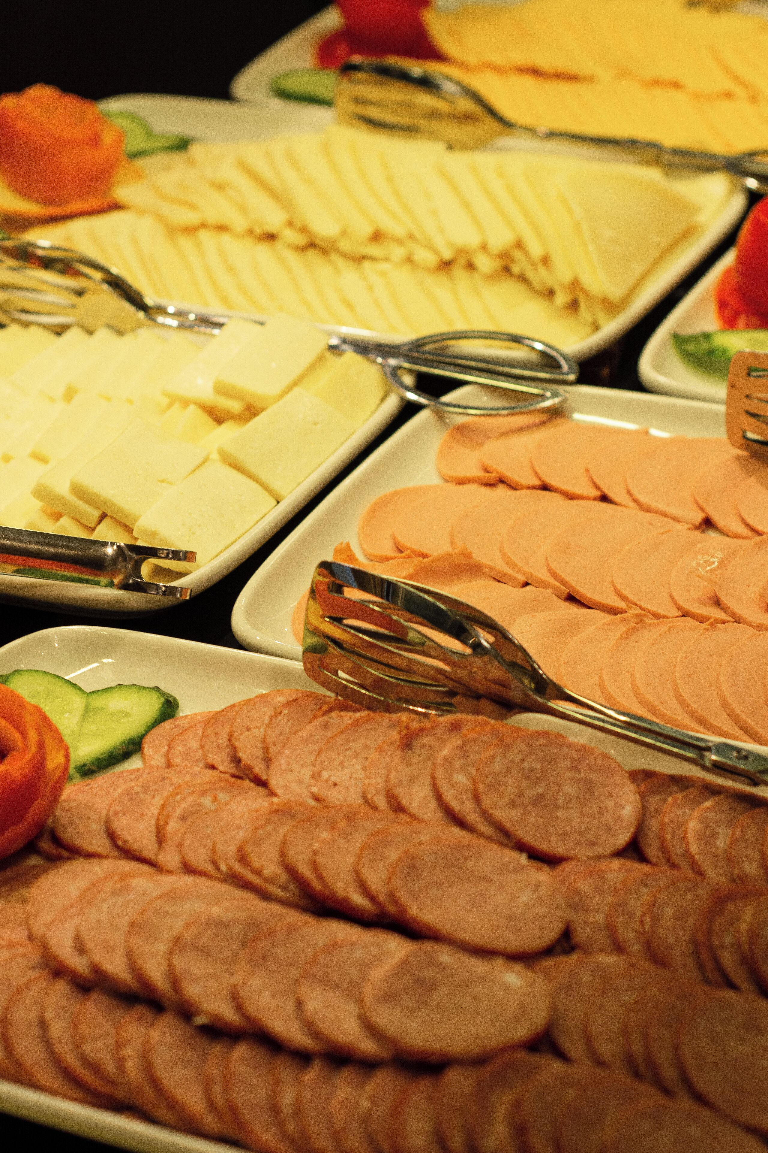 A buffet with various food items including sliced meats, cheeses, and vegetables.