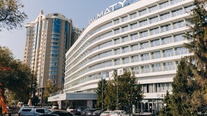 Um hotel moderno com fachada curva, várias varandas e uma placa de destaque.