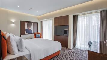 Une chambre d’hôtel dotée d’un grand lit, d’un téléviseur à écran plat, d’un bureau et offrant une vue sur l’extérieur.