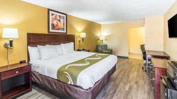 A hotel room with a large bed, bedside tables with lamps, a TV, a desk, and a chair.